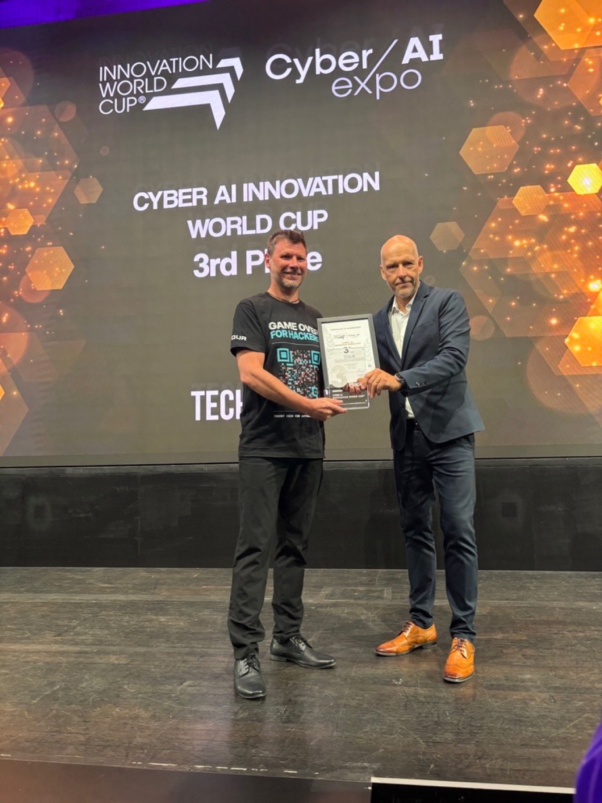 Adam Lundqvist receives the 3rd-place award of the Cyber AI Innovation World Cup on stage at Cyber / AI Expo Munich